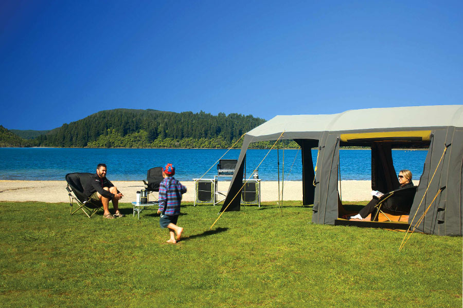 Family sitting on chairs next to their Zempire cabin tent outdoors