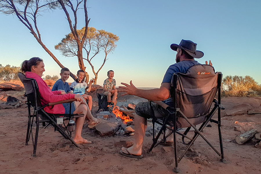Family with three kids relaxing around the campfire