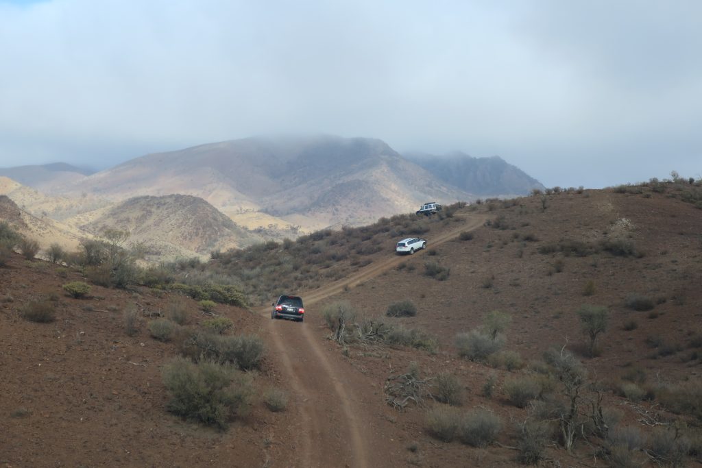 Convoy of cars on a 4WD track with rainclouds in the distance
