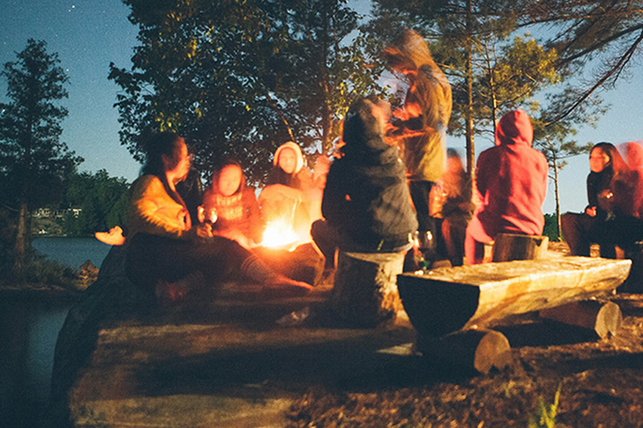A group of friends gathered around a campfire at night.