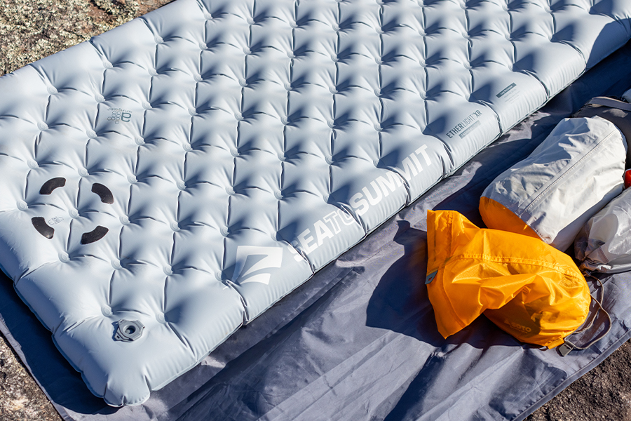 A Sea to Summit sleeping mat on a slab of rock, with the yellow stuff-sack to the side. 