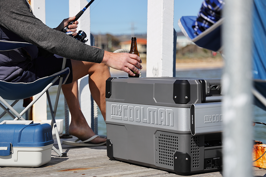 In this episode, Ben and Lauren sit down with myCOOLMAN's Technical Sales and Product Specialist, Charlie Graham. A man placing a beer on top of a myCOOLMAN, sitting in a chair on a jetty, fishing.