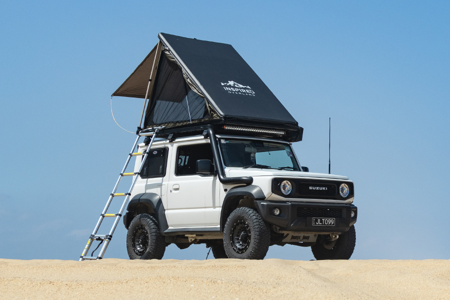 An Inspired Overland rooftop tent on a 4WD, parked on a beach. 