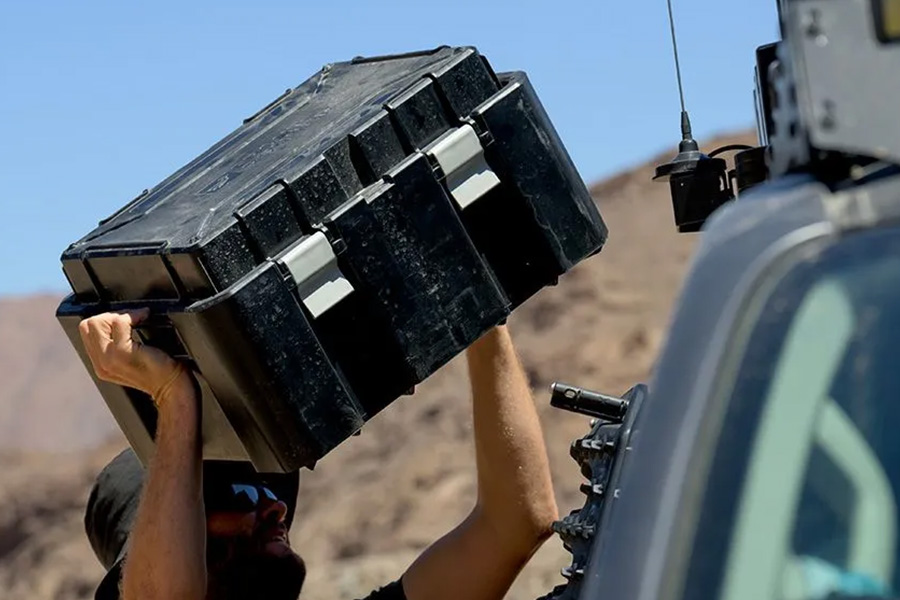 This week's episode is packed with content that stacks up! A camper lifting a box onto the top of his 4WD, which has a roof rack system.