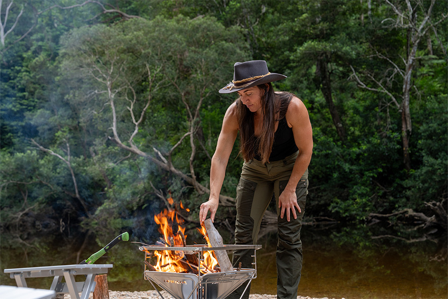 Brooke reveals five hidden camping gems that remain humbly off the beaten track. A female camper stoking a fire pit.