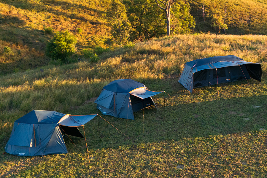 Three Blockout tents setup on a grassy area in the countryside.