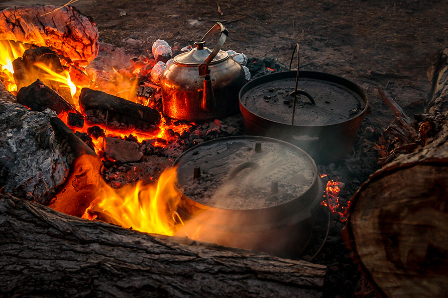 A camp oven suspended over a campfire. 